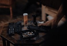 a person holding a remote control on top of a table next to a plate of food