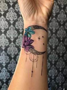 a woman's wrist with a flower on it and the moon in the background