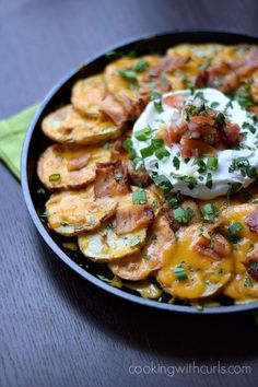 potato wedges with sour cream and bacon in a skillet on a green napkin