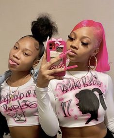 two women with pink hair are holding up cell phones