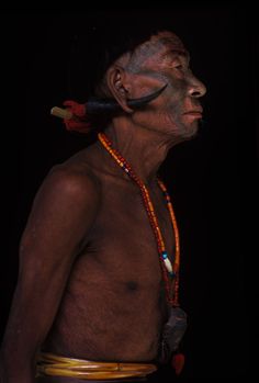 an old man with no shirt on wearing beaded necklaces and headdress