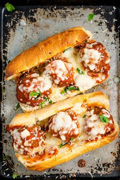 two meatball sub sandwiches on a baking sheet