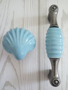 two blue glass knobs on a white wooden wall and one has a metal handle