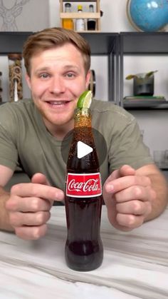 a man sitting at a table with a bottle of coca - cola