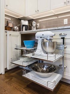 a kitchen with white cabinets and stainless steel appliances in the corner cabinet space, including an open shelf for mixing bowls