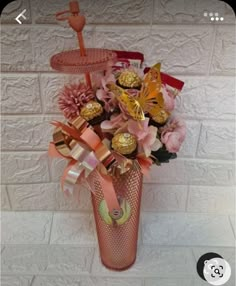 a vase filled with candy and flowers on top of a tiled floor next to a wall