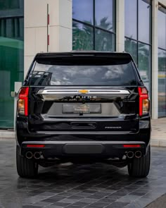 the back end of a black suv parked in front of a building