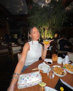 a woman sitting at a table with food and drinks