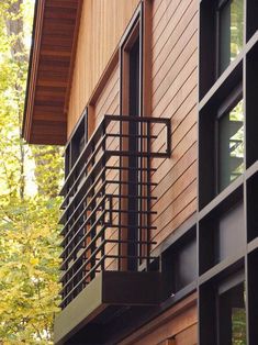 the side of a building with a metal railing on it's side and trees in the background