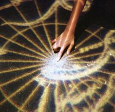 a person's hand touching the center of a circular object with light streaks on it