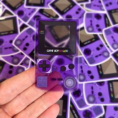 a hand holding up a purple gameboy