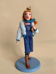 a doll with red hair and blue overalls holding a stuffed animal in her arms