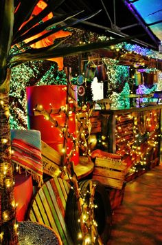 an outdoor bar with lights and decorations on the outside, along with wooden benches in front of it