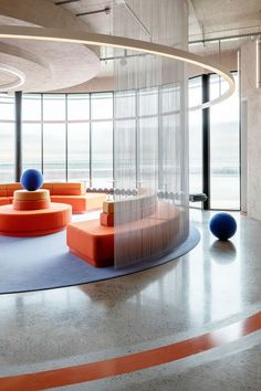 the circular room has orange and blue furniture in it, along with round balls on the floor