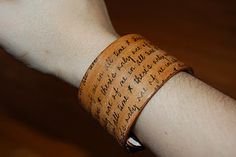 a person wearing a leather bracelet with writing on it