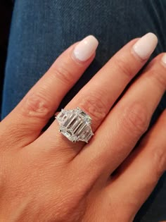 a woman's hand with a diamond ring on her left hand and white nails