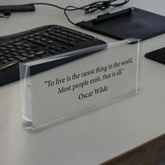 a clear acrylic sign sitting on top of a desk next to a keyboard