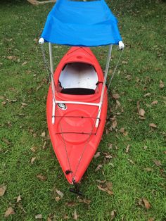 a red kayak with a blue cover on it sitting in the middle of grass