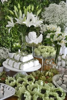 a table topped with lots of white flowers and cakes