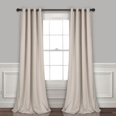 a white curtain hanging on the side of a window in a room with hardwood floors