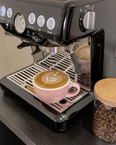 a coffee machine with two cups on top of it and some beans next to it