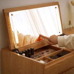 a person is holding their hand out in front of a wooden box with cosmetics inside