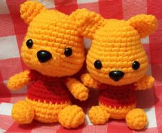 two crocheted teddy bears sitting next to each other on a red and white checkered tablecloth