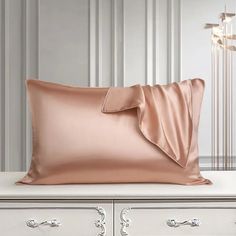 a pink pillow on top of a white dresser