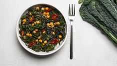 a white bowl filled with spinach and chickpeas next to some broccoli