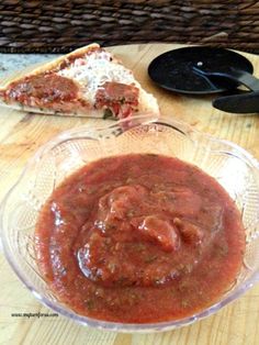 pizza sauce in a glass bowl next to a slice of pizza