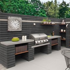 an outdoor kitchen with grill, table and chairs