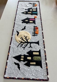 a long table runner decorated with black and white quilts, halloween decorations and pumpkins