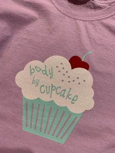 This cute t shirt will steal your heart and make you chuckle every time you wear it! 100% cotton t shirt in lavender with a cute cherry topped cupcake. frosting is a sparkly white vinyl. lettering says "body by cupcake". all colors as pictured. these shirts  are made to order. All shirts are waist length crop. Holly Springs Nc, Cupcake Frosting, Vinyl Lettering, Cute Tshirts, White Vinyl, Waist Length, Shirt Price, Cotton T Shirt, Frosting