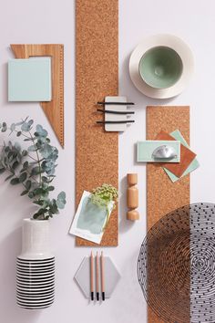 an assortment of office supplies on top of a cork board with place mats, plates and utensils