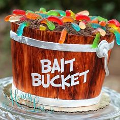 a cake that is decorated like a bucket with gummy bears in it on a glass plate