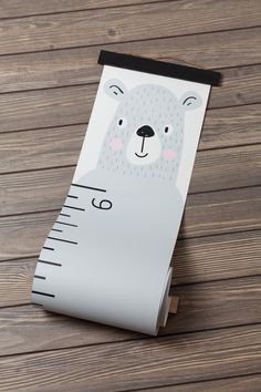 a ruler with a bear on it sitting on top of a wooden floor next to a wall