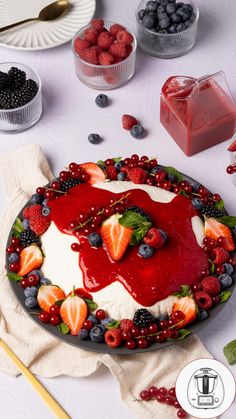 a cake with berries, strawberries and blueberries on it sitting on a table