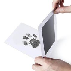 two hands are holding an open book with prints on it and one hand is pointing at the page