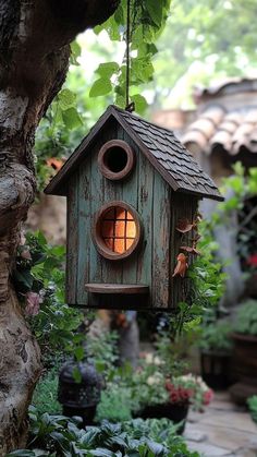 a birdhouse hanging from a tree in a garden