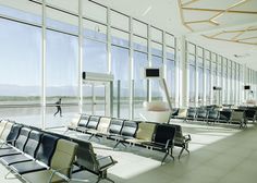 an empty waiting area with lots of chairs in front of large windows that look out onto the water