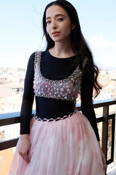 a woman standing on top of a balcony next to a railing wearing a pink tulle skirt