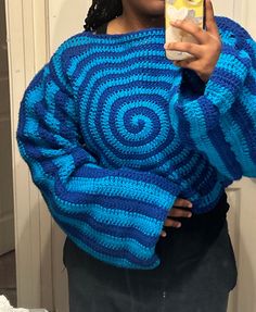 a woman is taking a selfie with her cell phone while wearing a blue crocheted sweater