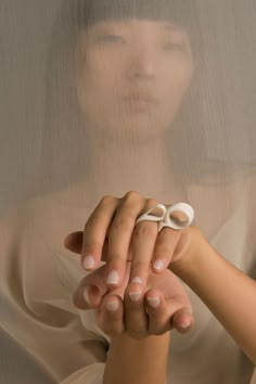 a woman is holding something in her hands while wearing a white shirt and beige nail polish