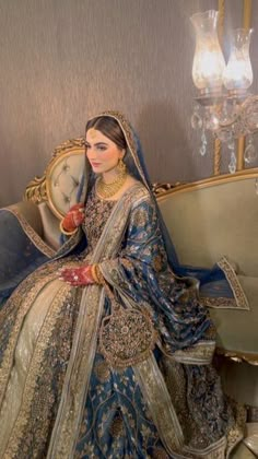 a woman sitting on top of a couch wearing a blue and gold wedding dress,