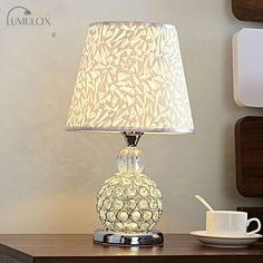 a table lamp sitting on top of a desk next to a cup and saucer