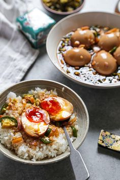 two bowls filled with rice and vegetables on top of a table next to other dishes