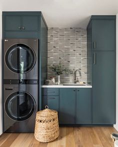 a washer and dryer in a room with wood flooring, blue cabinets and white walls