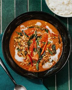 a pan filled with food on top of a table next to rice and spoons