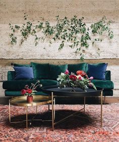 a living room with green velvet couches and flowers on the coffee table in front of it