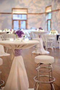 the table is set with white chairs and purple flowers on it, along with other tables